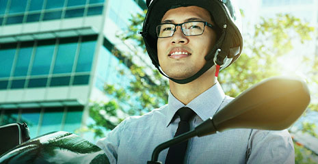 Homem de capacete e terno andando de moto