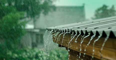 Foto de chuva forte caindo sobre telhado de uma casa.