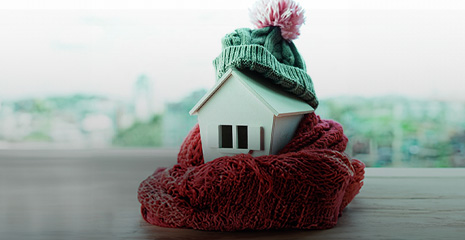 Casa em miniatura com gorro e cachecol.