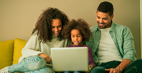 família reunida em sala de estar observando tela do notebook