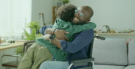homem sorrindo e abraçando criança sentado em uma cadeira