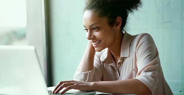 Mulher sorrindo enquanto olha para tela do computador