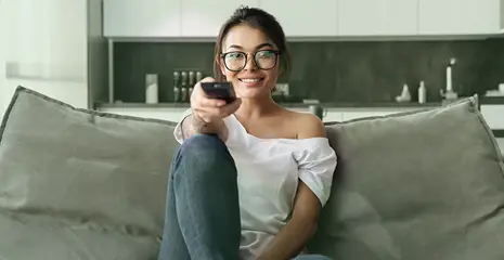 Foto de mulher apontando controle remoto da televisão para a câmera