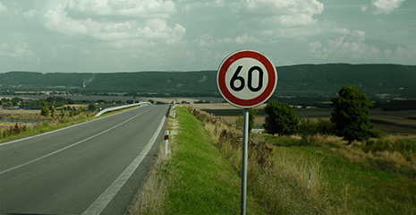 imagem de estrada com placa de sinalização em destaque indicando limite de velocidade