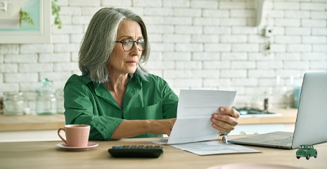 Mulher idosa de óculos analisando papel