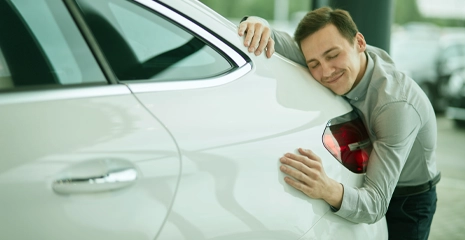Homem abraçando traseira do carro